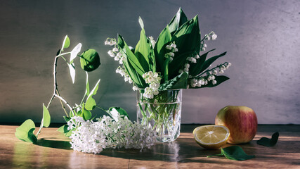 still life with a branch of white lilac and lilies of the valley in a glass mug