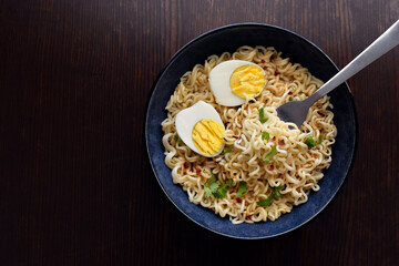 Instant noodles with egg, coriander and red chillies in a blue bowl.  Food from above.  Flat lay top view photo. 