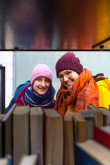Young lesbian couple looking through a bookshelf hole