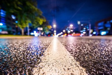 Night city after rain, the glowing lights of approaching cars. View from the level of the dividing line