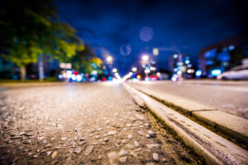Night highway with rails, cars go over it. View from a wide angle at the level of the asphalt - obrazy, fototapety, plakaty