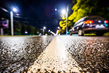 Night city after rain, parked the car at the roadside. View from a wide angle at the level of the dividing line