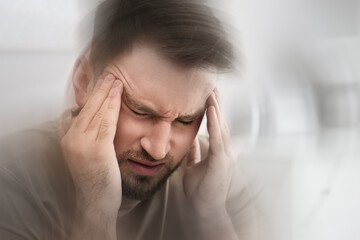 Young man suffering from migraine at home, closeup