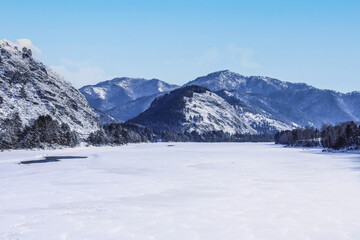 Mountains and frozen river in winter, sunny