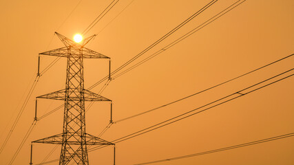 High power electricity pole silhouetted against the orange sky at dusk, Electric pole in India, with copy space