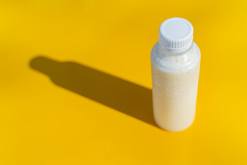 The juice bottle with its shadow on the yellow surface