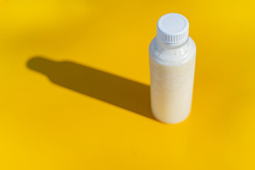 The juice bottle with its shadow on the yellow surface