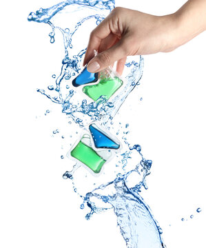 Splashes of water and woman holding laundry capsule on white background, closeup. Detergent pods