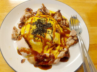 Creamy Omelet with Grilled Chicken and Teriyaki Sauce on rice with White tile plate in a luxury restaurant in Thailand.