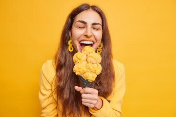 Overjoyed brunette woman eats tasty ice cream on mango flavor bites appetizing snack has dirty face...