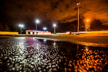 Night city after rain, lights illuminating the parking lot near the shopping mall. Wide angle view...
