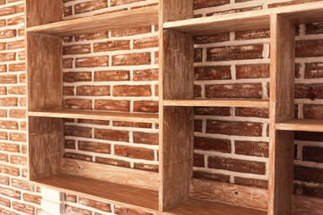 Empty shelves hanging on a red brick wall. Moving into a new house. A wooden carcas of a bookcase...