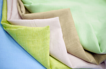 Pack pastel colored linen cloth fabrics in stack. Closeup multicolor towels one on one. Sewing items or tailoring objects concept. High quality horizontal photo