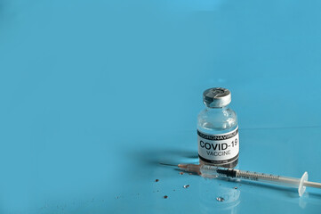 Coronavirus COVID-19 Vaccine Glass Bottle and syringe on blue surface with blue background at Thailand. Concept viruses spread throughout the world. Selective Focus.