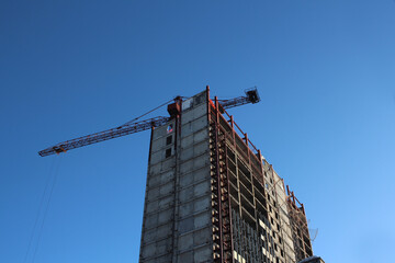 Fototapeta premium building frame skyscraper on a construction site with a crane in the sky