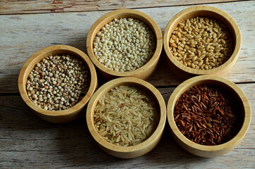 Brown Glutinious Rice, Red Jasmine Rice, Oat Rice, Barley Rice, Millet Rice, Brown Wheat Rice in wooden bowl on wooden table background.