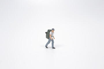 A Miniature people Backpacker walking on white board