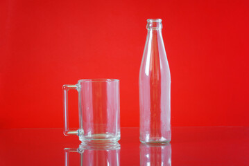 Transparent glass bottle and cap on a bright red background. Container for liquids. Free space for an inscription