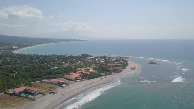 Aerial Lockdown Shot Of Waves Rushing Towards Coastline At Beach, Drone Flying Over Green Tress Against Sky On Sunny Day - Zambales, Philippines 
