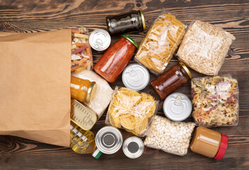 Food donations such as pasta, rice, oil, peanut butter, canned food, jam in a paper bag on brown...