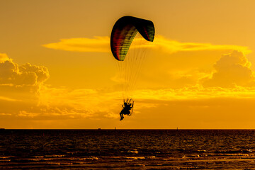 Paraglider fly in the sky above the sea.

