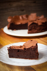 Slice homemade flourless chocolate cake serve on white plate. Free gluten dessert. Crunch top of cake and soft with moist with texture.