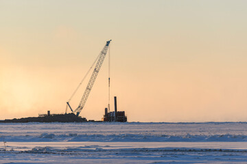 Fototapeta premium Barge with crane. Dredger working at sea. Sunset in Arctic sea. Construction Marine offshore works. Dam building, crane, barge, dredger.