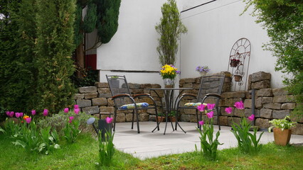 Gartenterrasse mit Sitzgruppe (Tisch und Stühle) im Frühling