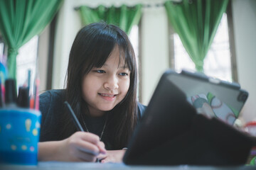 Asian little schoolgirl studying during her online lesson at home with smile and happy, social distance during quarantine,online education concept.