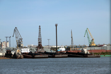 Naklejka premium Cityscape - view over river port with cranes and barges