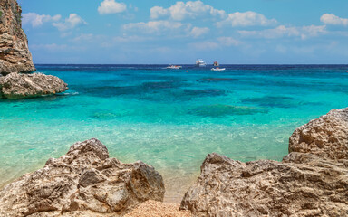 Sardinia, Italy. holidays. Cala Biriola Beach, rocky coastline, sea with crystal clear azure water, cruise boats far out at sea.
