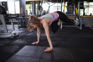 Fototapeta na wymiar Young woman exercising at gym, using trx system trainer