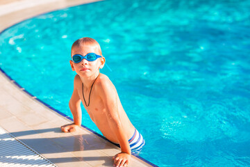 Cute happy little boy in goggles swimming and snorking in the swimming pool