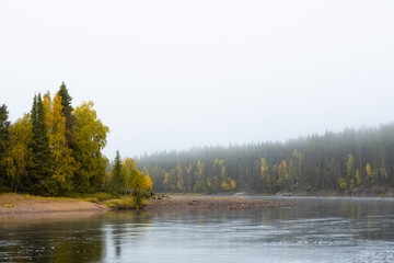 Fototapeta premium Autumn misty morning. River and colorful forest. Lapland, Scandinavia