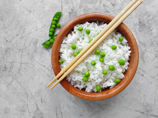 rice with green peas, sticks on concrete background