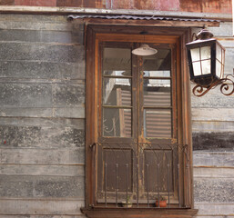 Old wooden window with bars and a lamp.