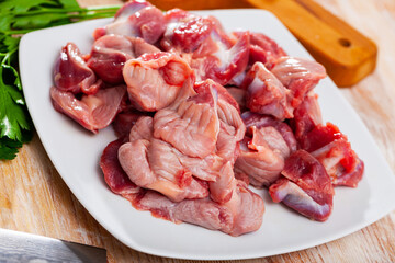 Picture of raw chicken gizzards and greens on wooden surface