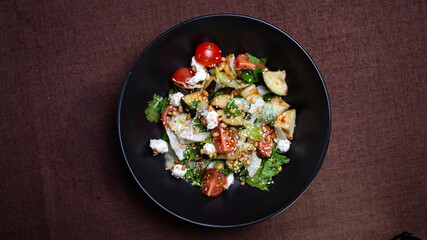 view from above salad with eggplant in sour sweet sauce in a black plate.