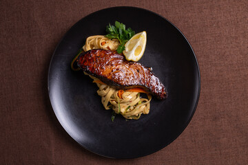 view from above pasta with salmon with soy sauce close-up on a plate