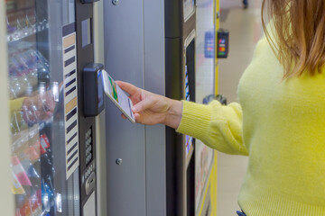 Close up view of woman paying for purchase at snack vending machine using smartphone. Contactless payment theme. - obrazy, fototapety, plakaty