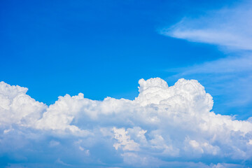 Naklejka na ściany i meble Beautiful white clouds in a bright blue sky on a warm summer day
