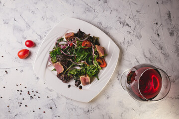 Top view fish salad with greens on a white plate