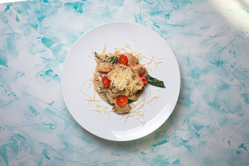 Pasta with hard cheese and meat with wine in the background.