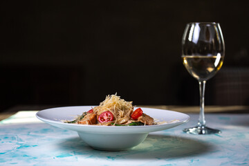 Pasta with hard cheese and meat with wine in the background.