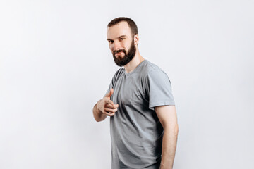 Portrait of cheerful young handsome man smiling looking at camera pointing finger forward on white background with space for advertising mock up