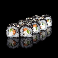 Roll Smoked California with cucumber, avocado, eel and black tobiko caviar on black with reflection. Close up. Japanese cuisine.