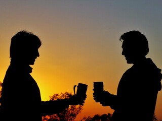 Two men toasting at sunrise in the mountains