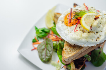 Egg in a cloud on grilled sandwiches with cumberland sausage, tomato and mayonnaise, all served with a fresh salad