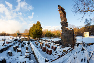 Remains of a burned down house with a brick oven in the middle of a snowy nature, a chimney on the...