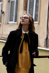 Teen girl in a white shirt, black stockings glasses on a walk in the old town